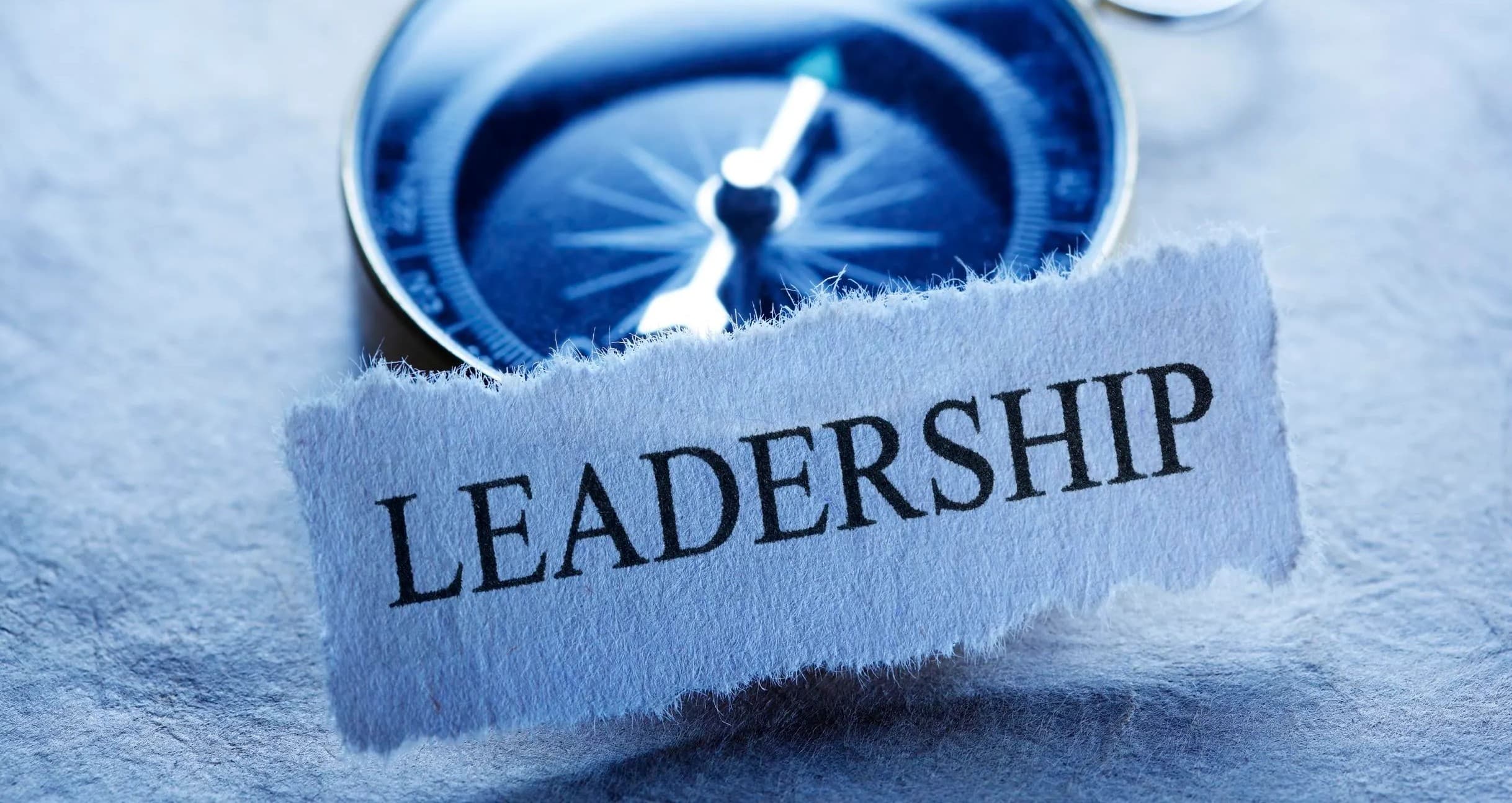 A compass beside a torn paper reading Leadership